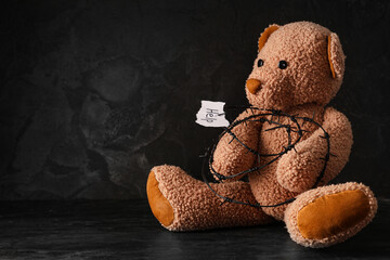 Paper piece with word HELP, barbed wire and toy bear on dark background. Domestic violence concept