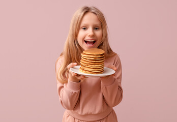 Little girl with tasty pancakes on beige background