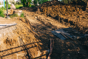 Fototapeta premium an open pit with a loader for laying pipes. a paved road to improve communications in the city. preparation of trenches for construction work