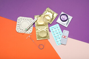 Contraceptive pills, condoms, intrauterine device and thermometer on color background, flat lay....