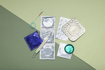 Contraceptive pills, condoms, intrauterine device and thermometer on color background, flat lay. Choice of birth control method