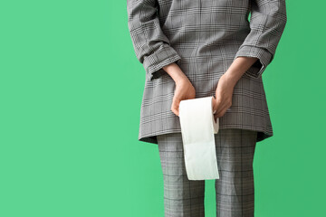 Young businesswoman with hemorrhoids and toilet paper on green background, back view