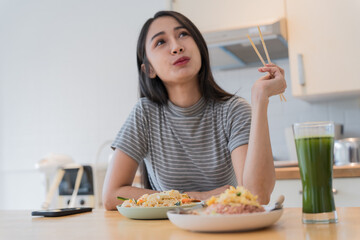 Obraz na płótnie Canvas Asian Girl  eating Thai food in kitchen counter Home delivery food feeling happy 