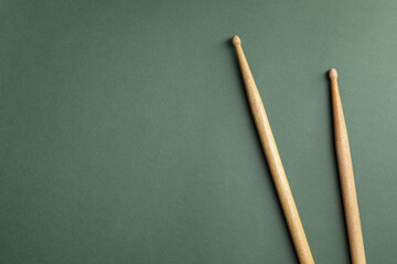 Two wooden drum sticks on olive background, top view. Space for text