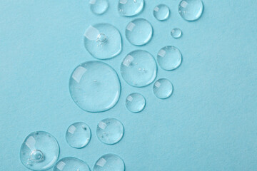 Drops of cosmetic serum on light blue background, top view. Space for text