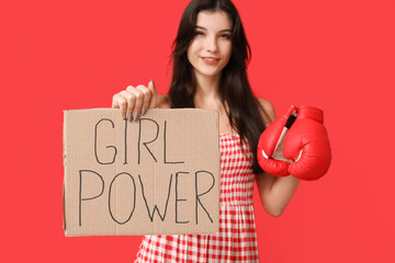 Young woman with sign GIRL POWER and boxing gloves on red background. Feminism concept