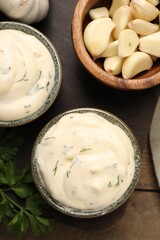 Tasty sauce with garlic and parsley on wooden table, flat lay