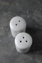 Salt and pepper shakers on dark textured table, above view