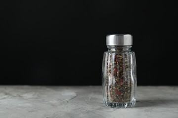 Pepper shaker on light textured table against black background. Space for text