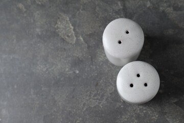 Salt and pepper shakers on dark textured table, above view. Space for text