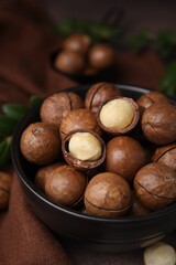 Tasty Macadamia nuts in bowl on table, closeup