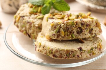 Tasty halva with pistachios and mint on table, closeup