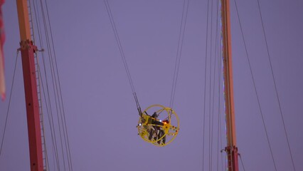 This video shows a sling shot carnival ride with an evening sky in the background. 
