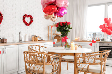 Bouquet of beautiful roses and burning candles on dining table in festive kitchen. Valentine's Day celebration