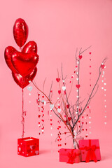 Tree branches with paper hearts, gift boxes and heart-shaped balloons on pink background. Valentine's Day celebration