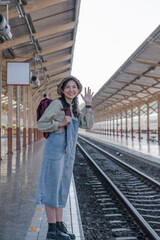 Young Asian woman in modern train station Female backpacker passenger waiting for train at train station to go on holiday.