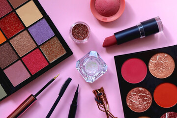 Various colorful make up products on pastel pink background. Top view.