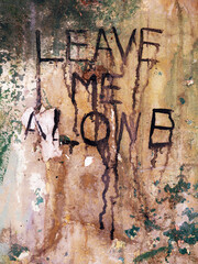 Leave Me Alone message on abandoned wall

