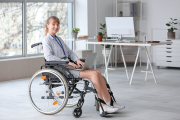 Young businesswoman in wheelchair working with laptop at office