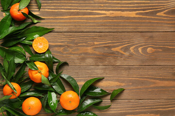 Many sweet mandarins and leaves on wooden background