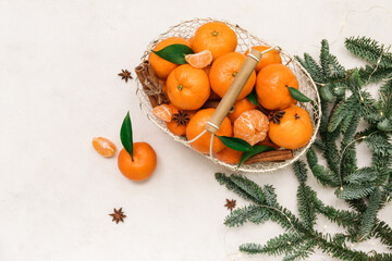 Basket of sweet mandarins with cinnamon, star anise and fir branches on white background