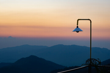 A white lamp with scenic view at sunset time with silhouette mountain background at Phu Chi Fa Forest Park in Chiang Rai, Thailand.