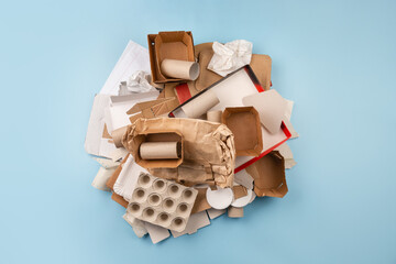 Separate collection of paper garbage. Paper stuff for recycle on blue background. Eco friendly concept. Recyclable paper waste on blue: cardboard, craft paper, egg carton, disposable cup. Zero waste.