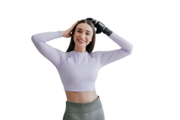 Cheerful young brunette in sportswear standing against wall and plant looks at camera  goes for training at gym happy to use her new artificial hand. Happy people after rehabilitation after injuries.