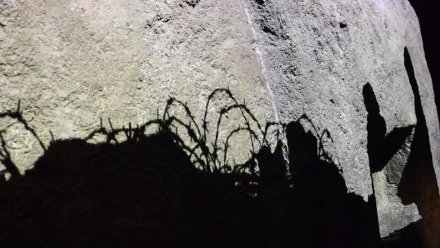 Shadows of walking soldiers and tranches with barbed wire.