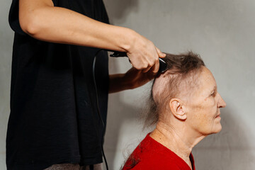 shaving woman because of a cancerous tumor. removal of hair on the head with an electric razor...