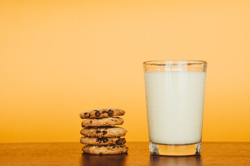 Delicious Breakfast: Cookies and Milk on a Wooden Table with an Orange Background.