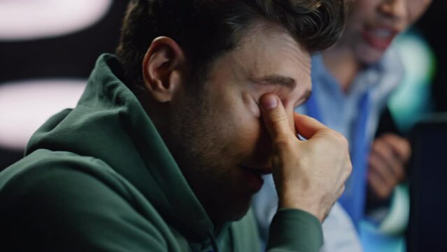 Tired developer rubbing eyes working at office late with woman colleague closeup