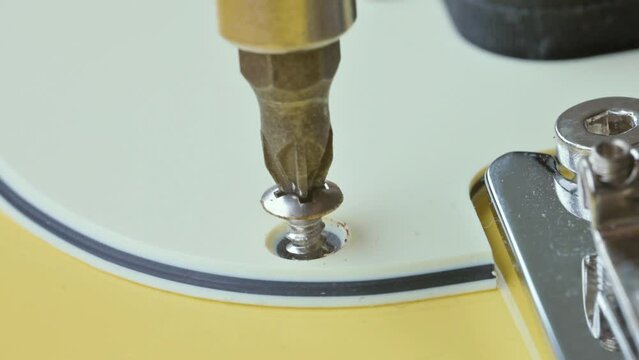 Guitar service concept. man unscrews a self-tapping screw. 4k video footage UHD 3840x2160