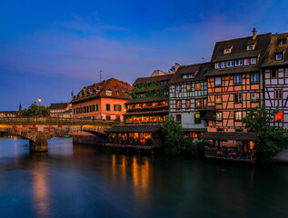 Fototapeta na wymiar Ornate traditional half timbered houses with blooming flowers along the canals in the Petite France district of Strasbourg, Alsace, France at sunset