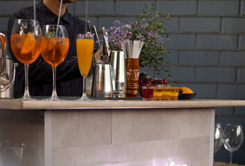 Glasses of cocktails on the bar. Bartender pours a glass of sparkling wine with red alcohol.