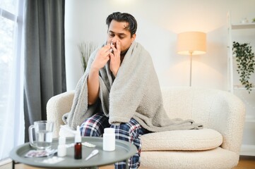 rhinitis, medicine and healthcare concept - sick indian man in blanket using nasal spray at home