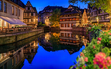Fototapeta na wymiar Ornate traditional half timbered houses with blooming flowers along the canals in the Petite France district of Strasbourg, Alsace, France at sunset
