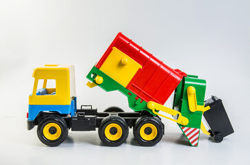 Multi-colored plastic toy trucks for children's games on a white background. Garbage truck.
