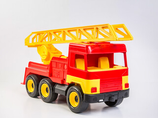 Multi-colored plastic toy trucks for children's games on a white background. Red fire truck with telescopic antenna.