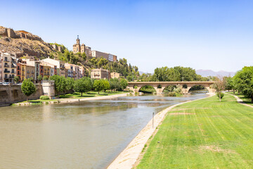 Sant Miquel old bridge over Segre river and a view to the Sant Crist in Balaguer, comarca of Noguera, Province of Lleida, Catalonia, Spain - obrazy, fototapety, plakaty