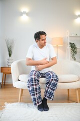 Sad exhausted guy of indian and arabian ethnicity, holds his hands on his stomach, grimaces from...