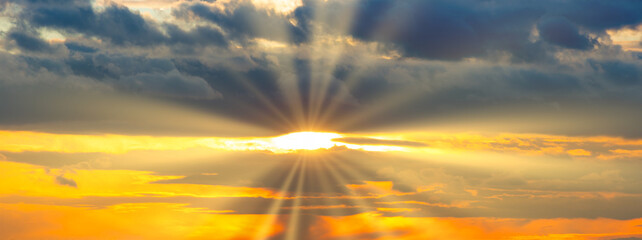 Sunset sky panorama with sunset clouds, sun rays and dramatic sky