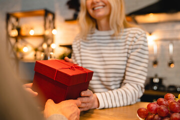 Cropped shot of happy wife receiving anniversary or St. Valentines gift from her husband during...