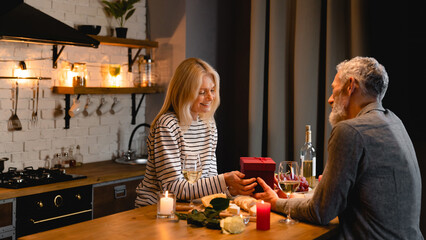 Blurred photo of happy caucasian couple having a romantic dinner in the kitchen - obrazy, fototapety, plakaty