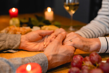 Close up photo of lover`s hands holding together with engagement ring on a date