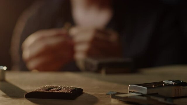 Unrecognizable goldsmith checking ring in dark studio