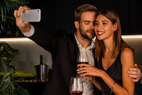Joyful young couple taking selfie while having romantic dinner at home