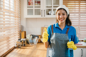Hygiene-conscious woman in apron and glove ready for housework. Holding spray bottle emphasizing...