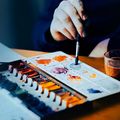  The artist mixes watercolor paints on the palette with a brush. The process of drawing. Creation.