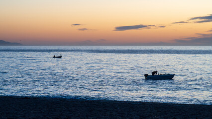 Pescador en su barco al amanecer en la costa de Granada, España